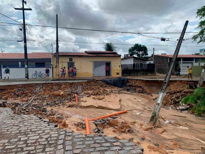 Cratera se abriu após chuva, na madrugada desta quarta (8) em Pitimbu, Zona Sul de Natal. Poste ficou torto e sustentado pelos fios — Foto: Mariana Rocha/Inter TV Cabugi